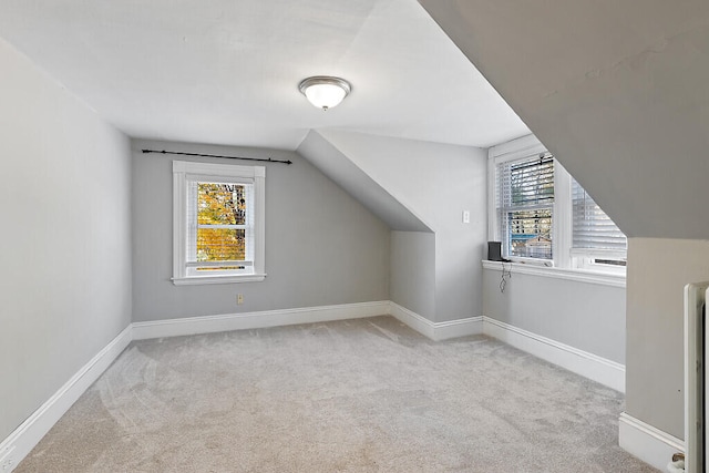 bonus room with lofted ceiling, light colored carpet, and a healthy amount of sunlight