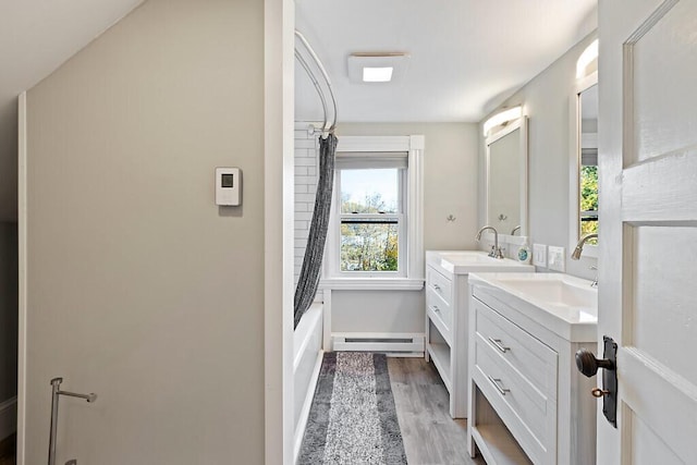 bathroom with wood finished floors, shower / bath combo, a baseboard radiator, and vanity