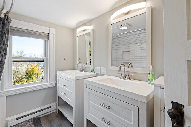 bathroom with vanity, tiled shower, baseboard heating, and hardwood / wood-style floors