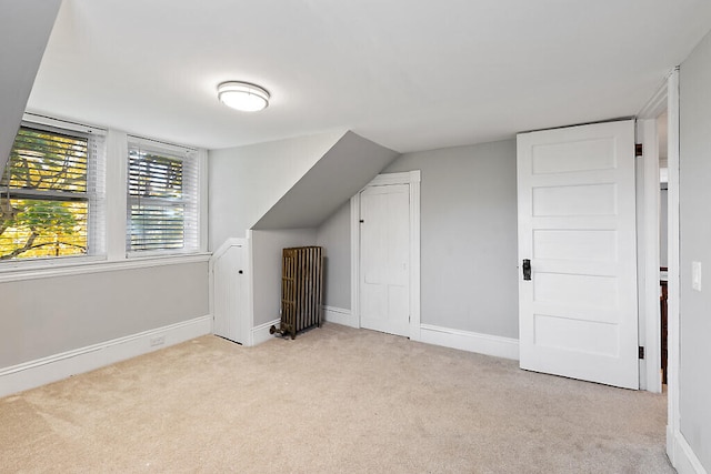 bonus room with light carpet, lofted ceiling, and radiator heating unit