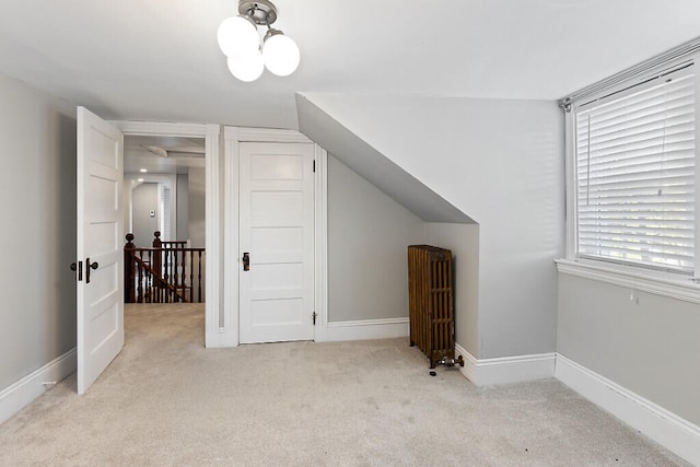 bonus room featuring vaulted ceiling, light carpet, and radiator heating unit