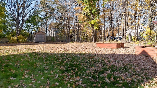 view of yard with a vegetable garden, an outdoor structure, a storage shed, and fence