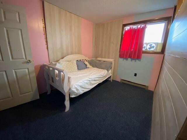 bedroom with dark carpet and a baseboard radiator