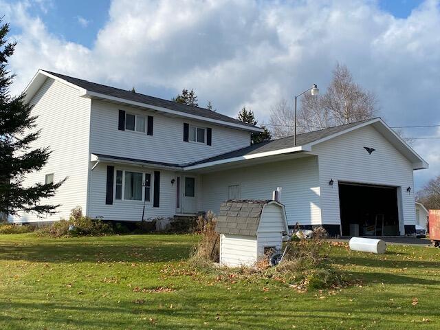 back of house with a garage and a yard