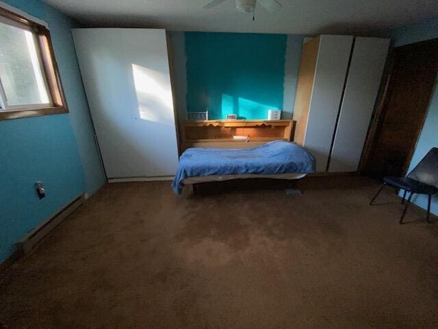 unfurnished bedroom with carpet flooring and baseboard heating