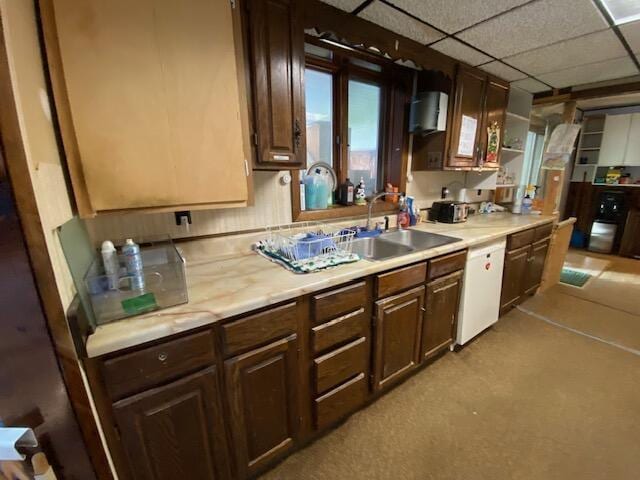 kitchen featuring dark brown cabinetry, dishwasher, sink, and a drop ceiling