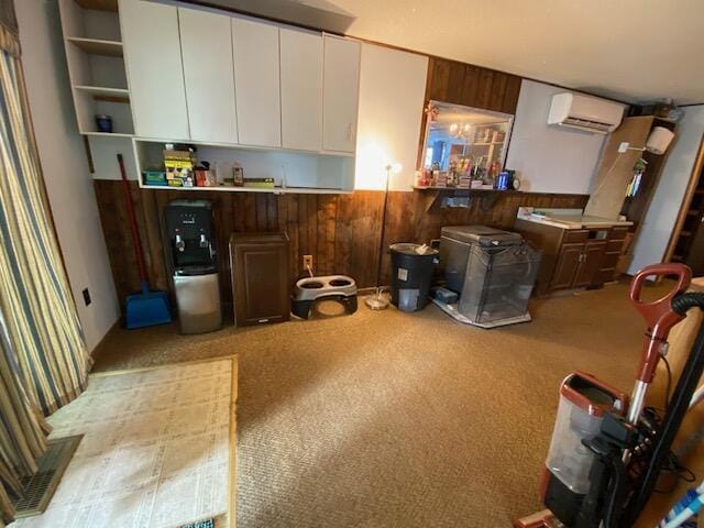 kitchen featuring white cabinetry, a wall mounted air conditioner, light colored carpet, and wood walls