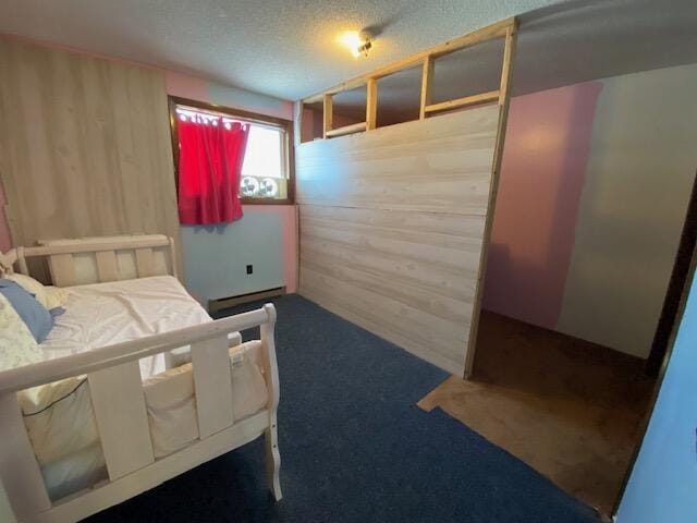 bedroom featuring a baseboard heating unit, carpet floors, a textured ceiling, and wooden walls