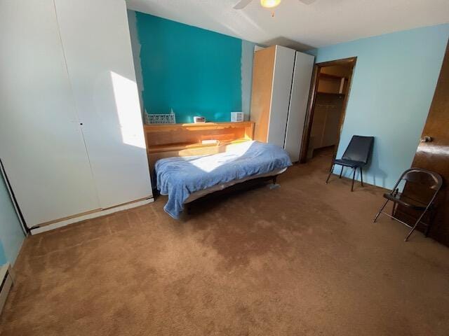 carpeted bedroom with ceiling fan and a baseboard heating unit