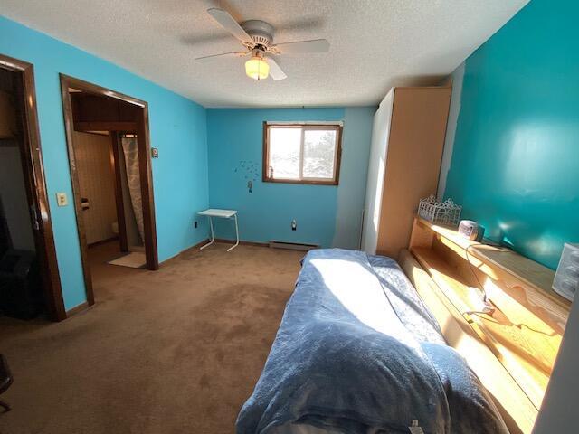 unfurnished bedroom featuring baseboard heating, ceiling fan, light carpet, and a textured ceiling