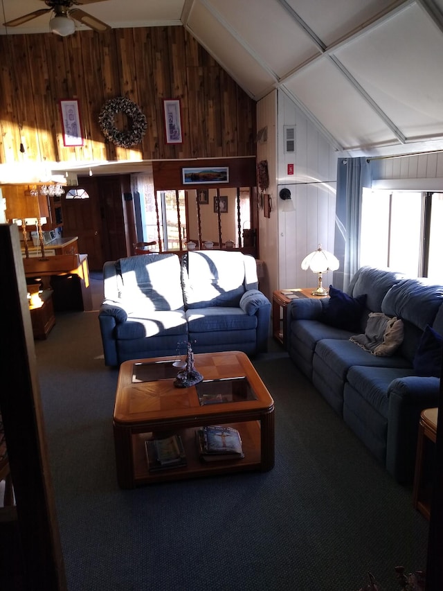 carpeted living room featuring wooden walls, ceiling fan, and vaulted ceiling