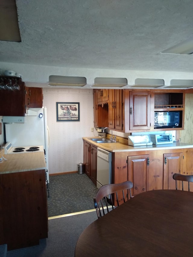 kitchen featuring white dishwasher, dark carpet, and sink