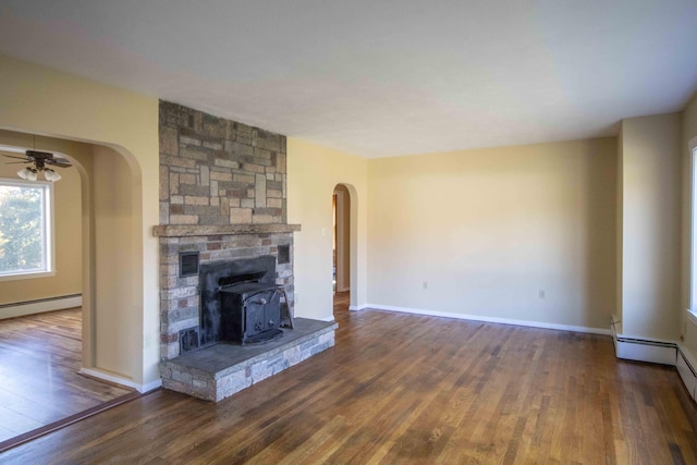32 Morison Ave, Wells, ME 04090 - unfurnished living room with wood finished floors, arched walkways, baseboard heating, baseboards, and a wood stove