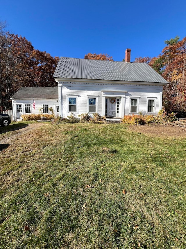 view of front facade featuring metal roof, a chimney, and a front yard