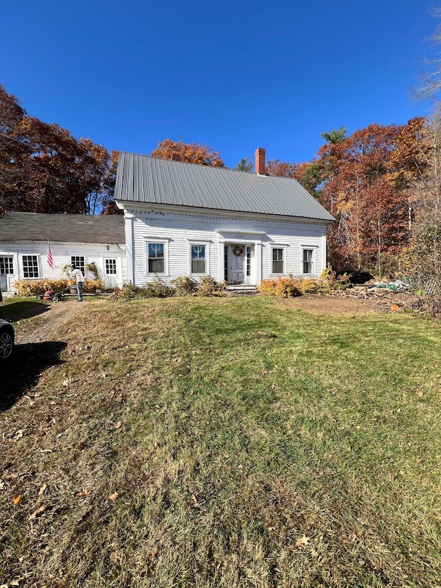 view of front of property with metal roof, a chimney, and a front yard