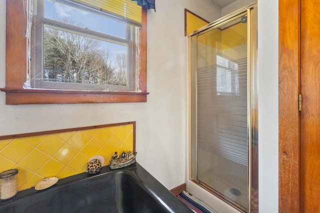 bathroom featuring tasteful backsplash and a shower with shower door