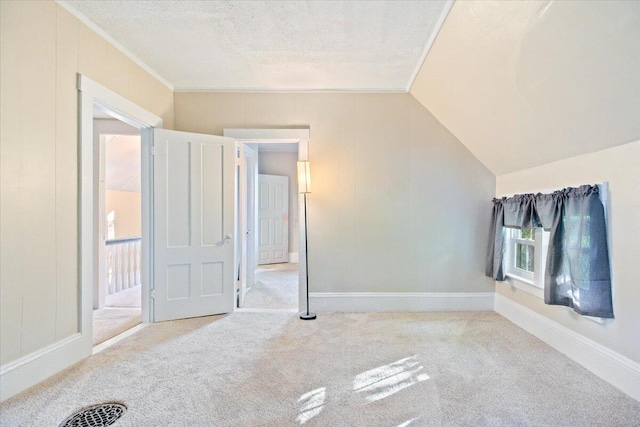 unfurnished bedroom featuring a textured ceiling, lofted ceiling, light colored carpet, and ornamental molding