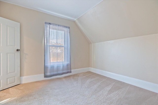 additional living space featuring vaulted ceiling and light colored carpet