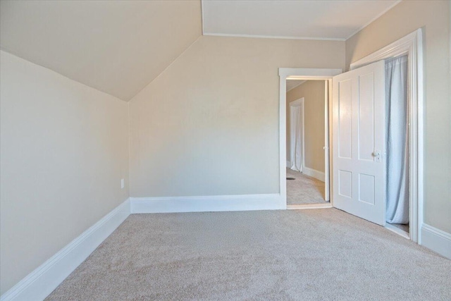 unfurnished room featuring vaulted ceiling and light colored carpet