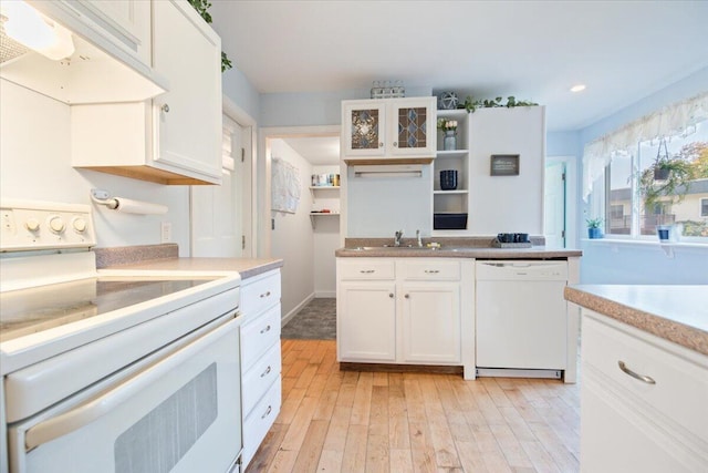 kitchen featuring white cabinetry, light wood-type flooring, range hood, sink, and white appliances