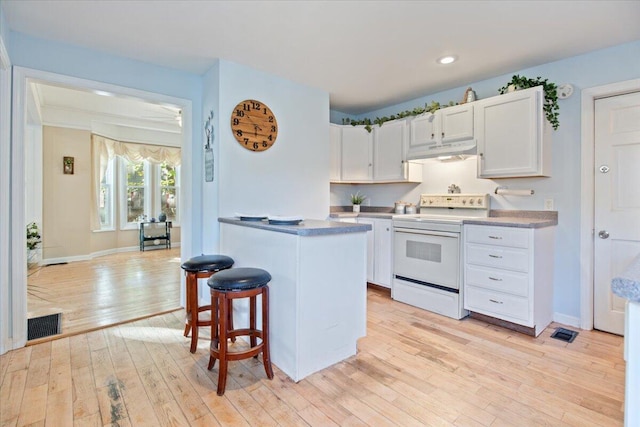 kitchen featuring a breakfast bar area, white cabinets, light hardwood / wood-style flooring, and white electric stove