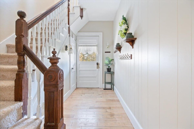 foyer entrance with light hardwood / wood-style floors and wooden walls