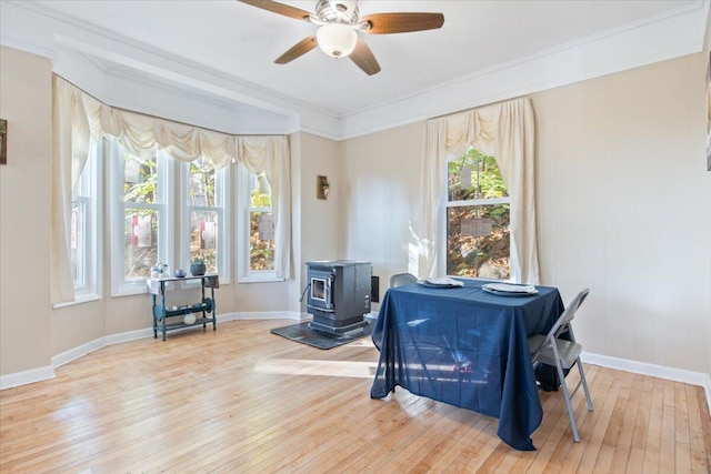 interior space with light hardwood / wood-style flooring, a wood stove, ceiling fan, and crown molding