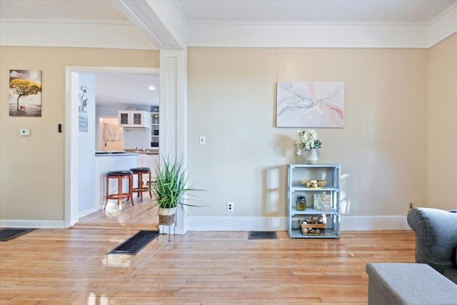 sitting room featuring ornamental molding and light wood-type flooring