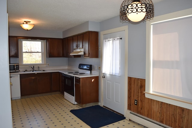 kitchen featuring white appliances, a baseboard heating unit, sink, a textured ceiling, and wooden walls