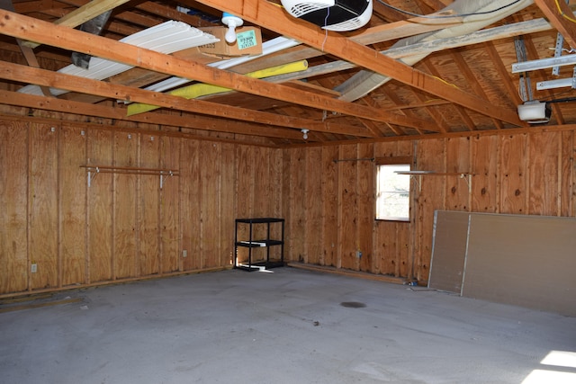 garage with a garage door opener and wooden walls