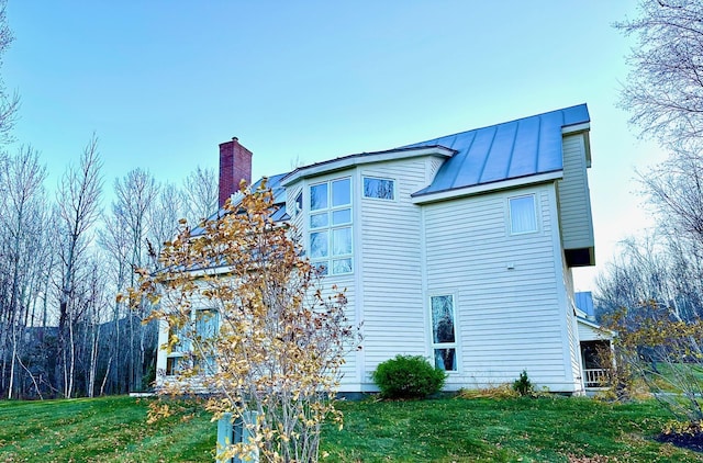 6071 Village On The Green Rd Unit G-11, Carrabassett Valley, ME 04947 - view of home's exterior with a standing seam roof, a chimney, a yard, and metal roof