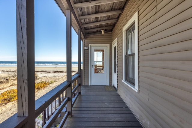 wooden terrace with a water view and a view of the beach