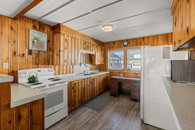 kitchen with white appliances, dark wood-type flooring, sink, and wooden walls