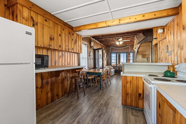 kitchen with white appliances, wood walls, dark hardwood / wood-style flooring, kitchen peninsula, and ceiling fan