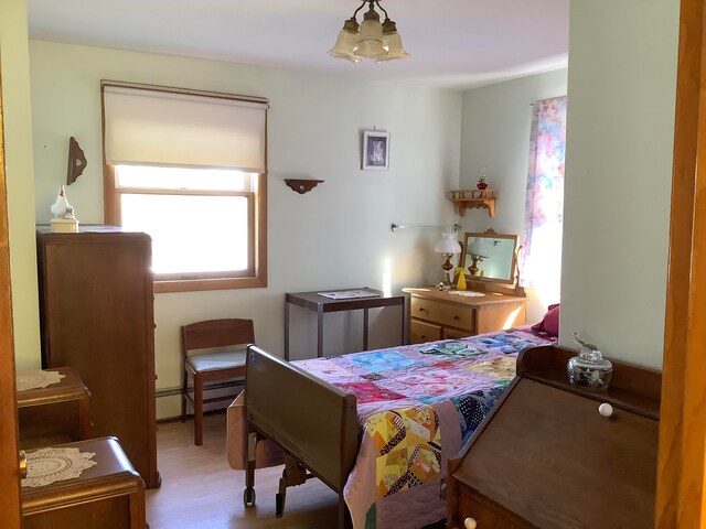 bedroom featuring a baseboard radiator, a chandelier, and hardwood / wood-style flooring