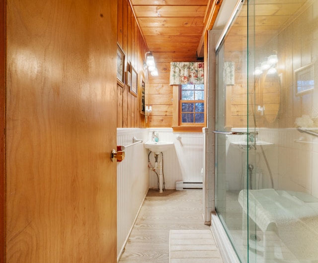 bathroom with wood walls, wooden ceiling, a baseboard heating unit, an enclosed shower, and wood-type flooring