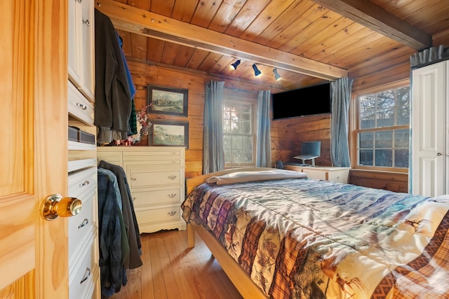 bedroom with beamed ceiling, wood walls, light wood-type flooring, and wooden ceiling