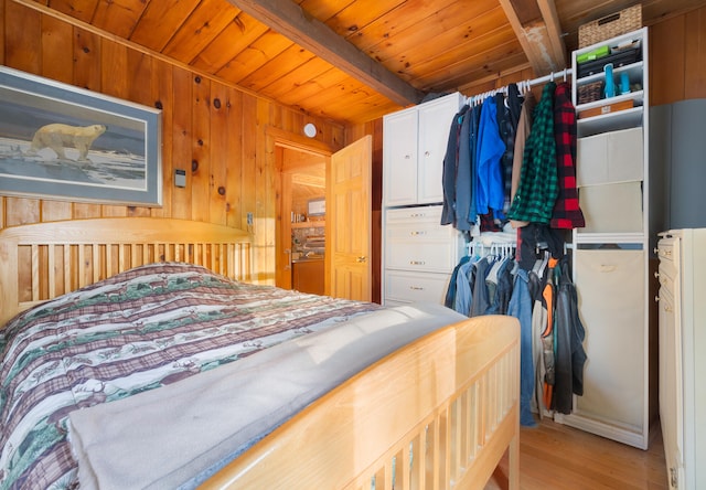 bedroom featuring beamed ceiling, wood walls, light wood-type flooring, and wooden ceiling