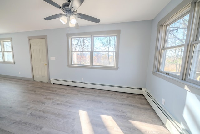 spare room with baseboard heating, plenty of natural light, and light wood-type flooring