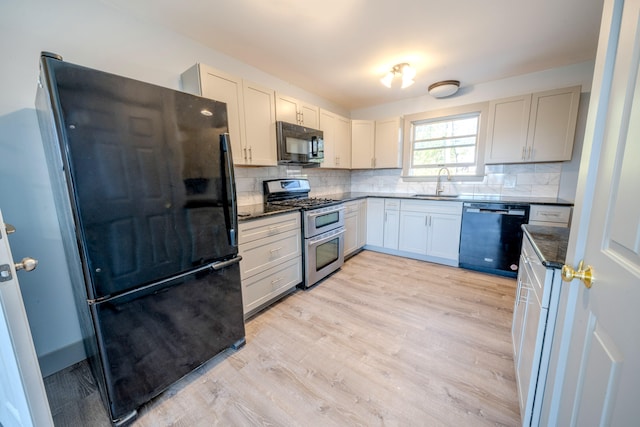 kitchen featuring sink, black appliances, light hardwood / wood-style flooring, and backsplash