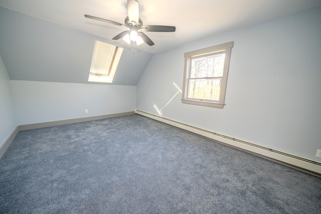 additional living space with vaulted ceiling with skylight, a baseboard heating unit, carpet flooring, and ceiling fan