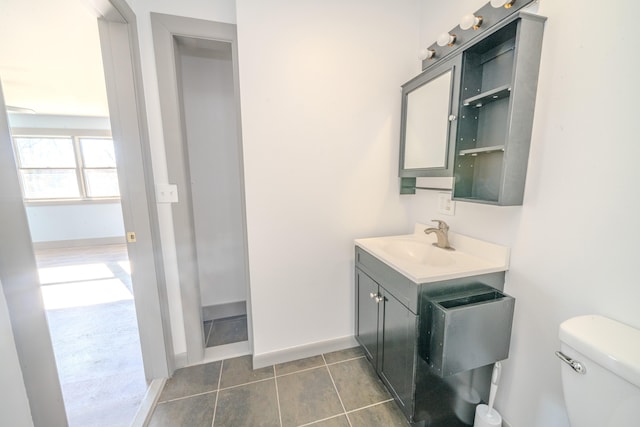 bathroom with toilet, vanity, and tile patterned floors