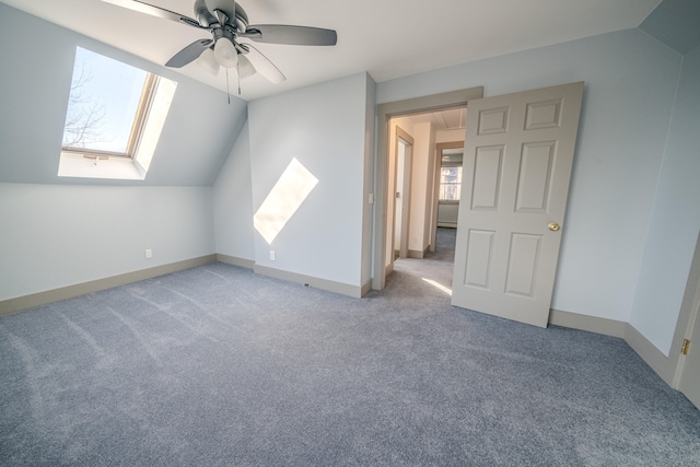 additional living space featuring carpet, vaulted ceiling with skylight, and ceiling fan