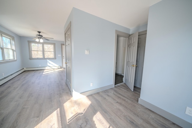 spare room featuring baseboard heating, light hardwood / wood-style flooring, and ceiling fan