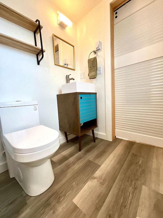 bathroom with vanity, toilet, and wood-type flooring