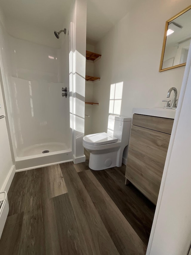 bathroom with a shower, vanity, wood-type flooring, and toilet