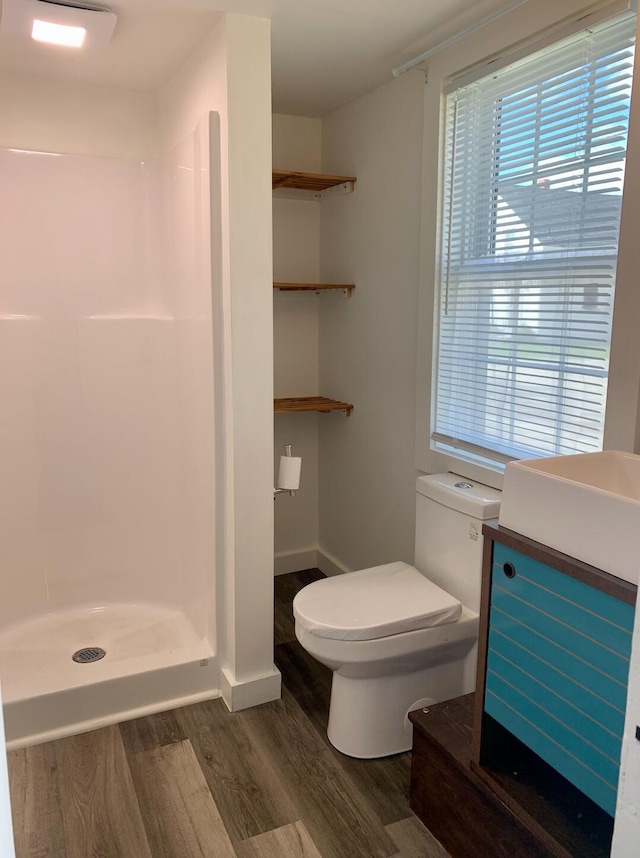 bathroom featuring toilet, wood-type flooring, and walk in shower