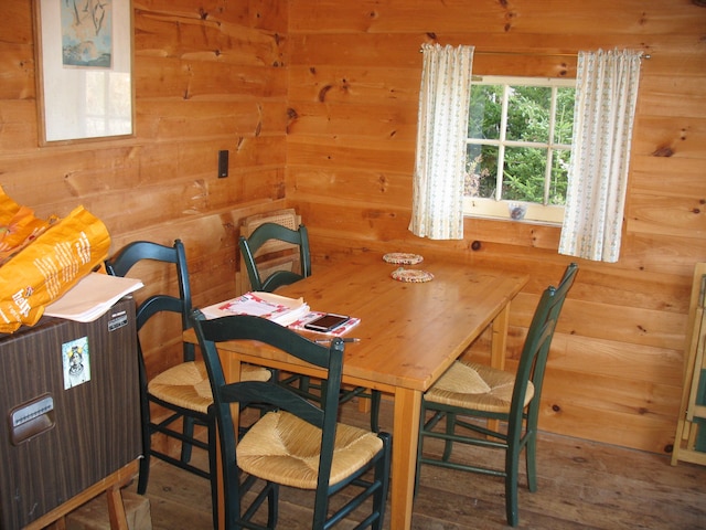 dining space featuring hardwood / wood-style flooring and wooden walls