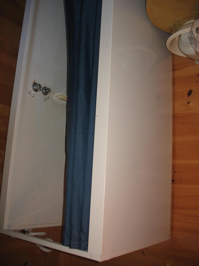 bathroom featuring wooden walls and a shower with shower curtain