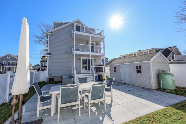 back of property with a balcony, a storage shed, and a patio area